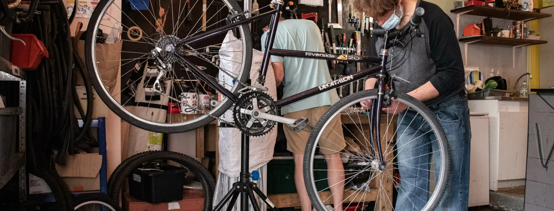 Deux personnes travaillent ensemble sur un vélo suspendu au pied de réparation.